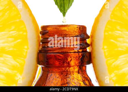 Gocciolando l'olio essenziale di agrumi in una bottiglia su sfondo bianco. Foto Stock