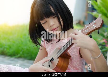 Ragazza asiatica che gioca l'ukulele Foto Stock