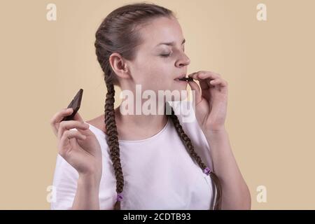 La ragazza ha un sapore di cioccolato. La ragazza sta godendo il gusto del cioccolato. Deliziatevi con il gusto del cioccolato. Giornata del cioccolato. Giorno dei dolci. La ragazza è sparata Foto Stock