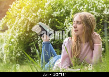 Bella ragazza-adolescente bionda sognare in una giornata di sole sul erba Foto Stock