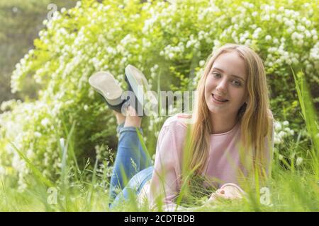 Bella ragazza-adolescente bionda sognare in una giornata di sole sul erba Foto Stock