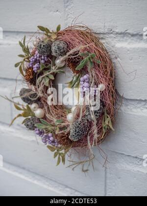 Bella corona di fiori che pende su una parete di mattoni bianchi Foto Stock