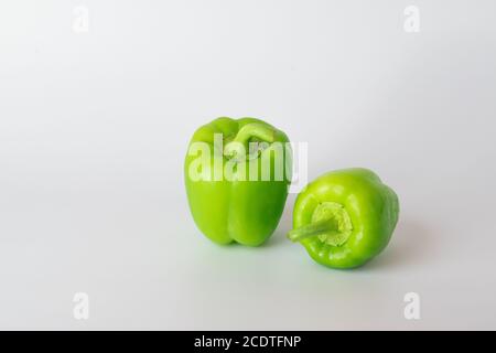 Due peperoni verdi su sfondo bianco. Foto Stock