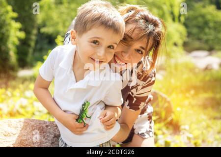 Felice piccolo ragazzo giocando con sua madre nel parco della città su un estate giornata di sole. La madre e il figlio nel parco vicino al laghetto. Foto Stock