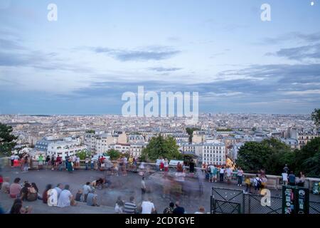 Parigi, Francia. 2019, agosto. Tramonto su Parigi da Montmartre alla basilica del Sacro cuore e persone sedute sulle scale in una giornata estiva nuvolosa. Tetti Foto Stock