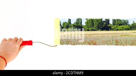 Una persona che dipinge un paesaggio su una parete bianca con una spazzola a rullo Foto Stock