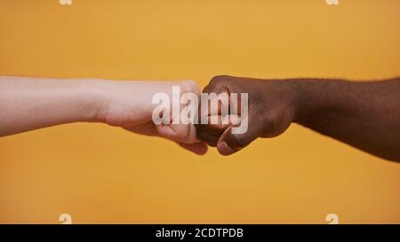 Fist to Fist - mani bianche e nere - concetto di partenariato e solidarietà. Foto di alta qualità Foto Stock