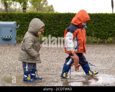 ritratto di due fratelli maschi e femmine, di 3 e 5 anni, che camminano in una pozza Foto Stock