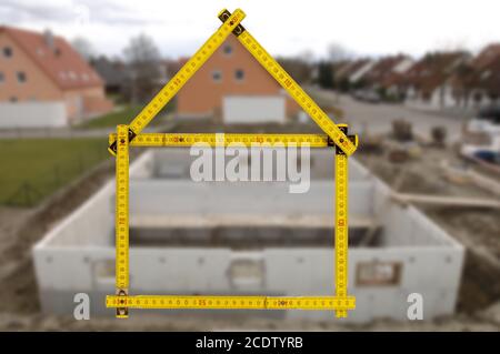 Metro piegato nella forma di una casa in mano a un agente Foto Stock