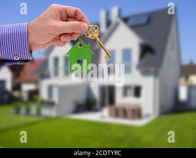 Chiave di casa sulla corona nella mano di agente immobiliare Foto Stock