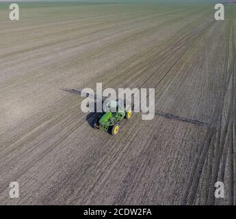 Trattore con sistema incernierato di irrorazione di pesticidi. Concimazione con un trattore, sotto forma di aerosol, sul campo d'inverno Foto Stock