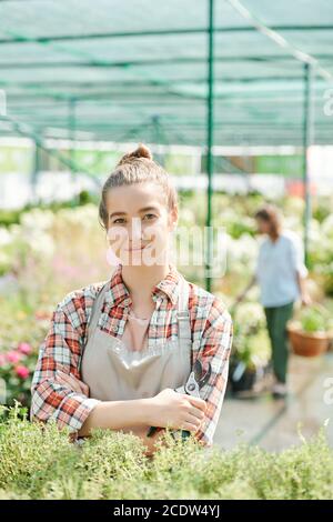 Giovane giardiniere di successo in abbigliamento da lavoro che tiene pinze e braccia incrociate dal petto Foto Stock