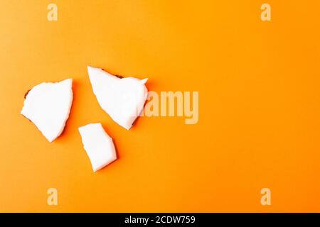 Happy Coconuts giorno concetto, fresco noce di cocco pezzi gruppo fette, studio girato isolato su sfondo arancione Foto Stock