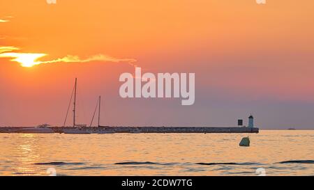 Tramonto sulla costa di Porec in Croazia. Sullo sfondo il faro dell'isola Sveti Nikola Foto Stock