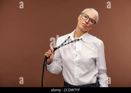 Giovane donna con capelli biondi corti tinti, piercing nel naso e tatuaggi sulle dita Foto Stock