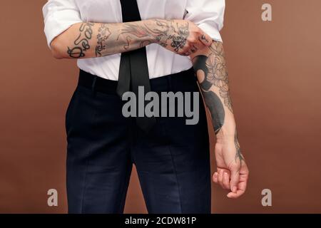 Femmina maschile in formalwear mostrando le sue braccia coperte di tatuaggi Foto Stock