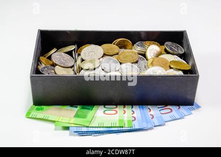 Monete di diverse confessioni in un salvadanaio box. La carta di rubli sotto il salvadanaio. Le nuove banconote della Russia Foto Stock