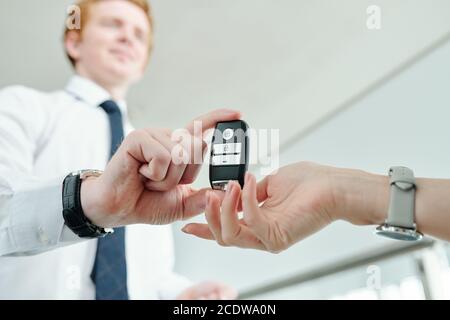 Mano di giovane donna che prende il sistema di allarme del telecomando di la sua nuova auto Foto Stock