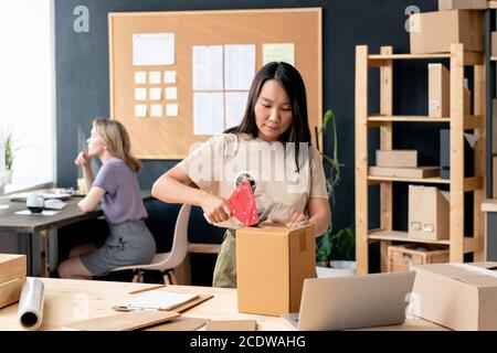 Giovane lavoratrice asiatica di negozio online o negozio-room ordini di imballaggio Foto Stock