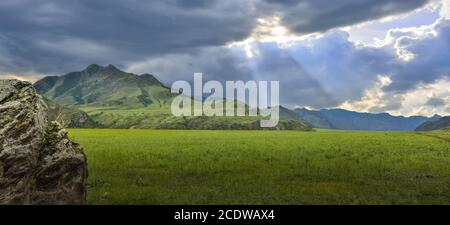 Il sole splende attraverso le nuvole sulle catene montuose e sulla valle - vista panoramica Foto Stock