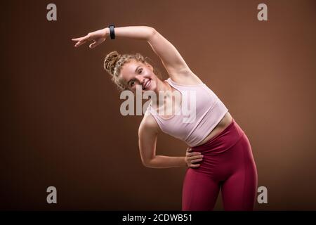 Allegra donna in abbigliamento sportivo in piedi davanti alla fotocamera e. esecuzione di piegature laterali Foto Stock