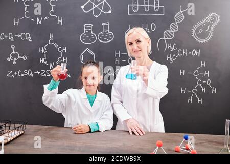 Studentessa e insegnante riuscito di chimica in whitecoats che tiene i tubi Foto Stock