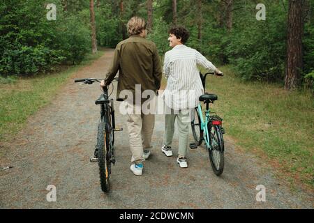 Vista posteriore di felice giovane marito e moglie in casualwear parlare l'un l'altro Foto Stock
