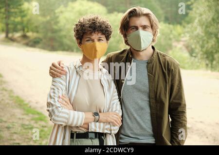 Felice giovane coppia affettuosa in maschere e casualwear protettivi fatti a mano Foto Stock