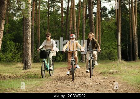 Felice famiglia di giovane marito, moglie e figlio a cavallo biciclette lungo il percorso forestale Foto Stock