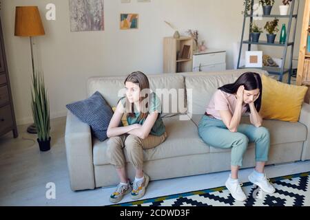 Infelice ragazza con le braccia incrociate e la sua madre stressata con la testa nelle mani Foto Stock