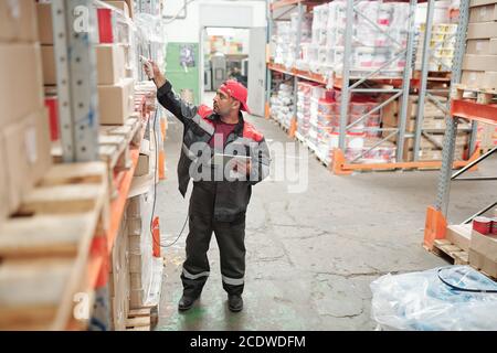 Gestore di corse miste o lavoratore di magazzino in qr a scansione uniforme codici Foto Stock