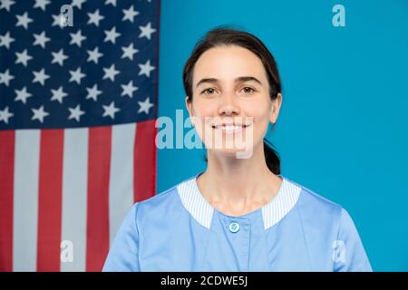 Cameriera giovane e sicura in uniforme blu che ti guarda con sorridi Foto Stock