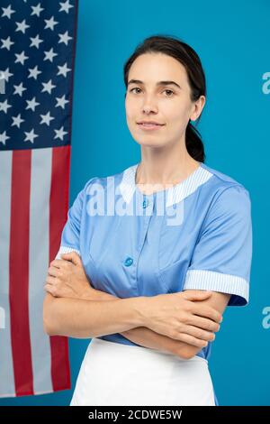 Giovane confidente cameriera in uniforme blu che attraversa le braccia torace Foto Stock