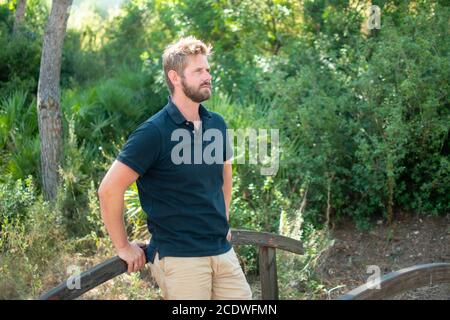 Bell'uomo poggiato su un ponte di legno in una casata Foto Stock