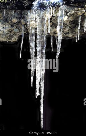 Iciclette appese da vicino, isolate su sfondo nero Foto Stock