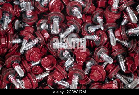 Vista dall'alto della struttura dello sfondo delle viti per tetti. Sfondo rosso viti copertura. А mazzetto di viti autofilettanti per il fissaggio del tetto con teste rosse Foto Stock