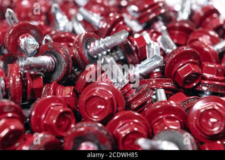 Immagine macro di una vista della struttura di sfondo delle viti del tetto. Sfondo rosso viti copertura. А mazzetto di viti autofilettanti per il fissaggio del tetto con rosso Foto Stock