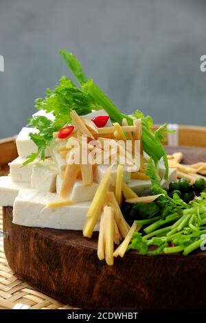 Materia prima per cuoco di tofu fritto con salsa, zenzero, pepe, fetta di tofu bianco, spezie pronte per cucinare sul tagliere, semplice cibo vegano fatto in casa Foto Stock