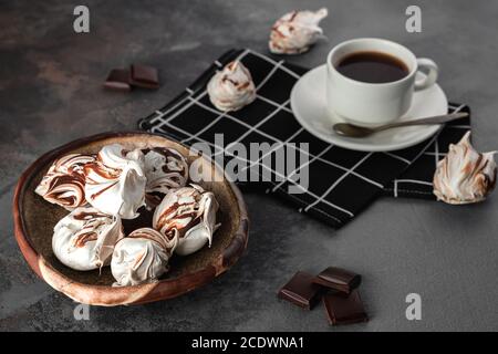 Composizione di natura morta con molte meringhe bianche e al cioccolato. Tazza di caffè su fondo grigio di cemento. Concetto di cibo e cottura casalinga in stile rustico Foto Stock