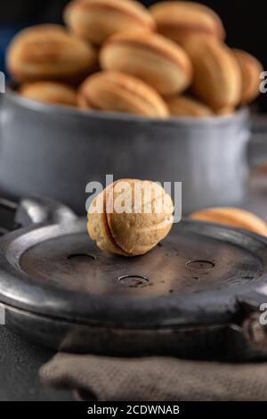 Composizione di natura morta con un biscotto dolce a forma di noci su una teglia da forno. Sfondo sfocato con delizioso dessert Foto Stock