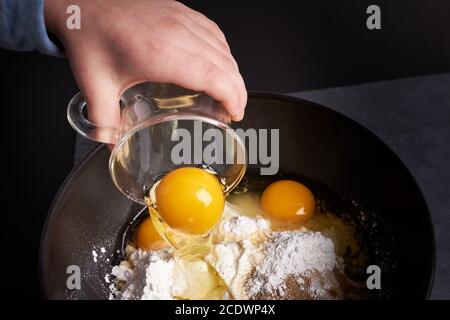 Il bambino versa l'uovo nel recipiente di miscelazione Foto Stock