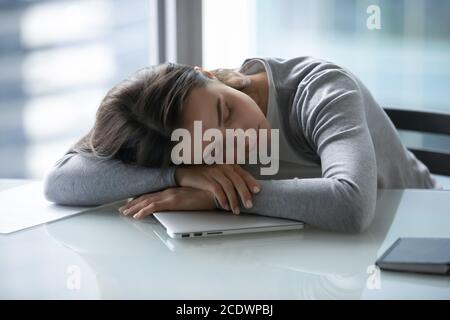 Stanca esausta giovane donna d'affari addormentata alla scrivania Foto Stock