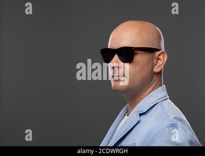 Uomo calvo in bicchieri di nero su sfondo grigio Foto Stock