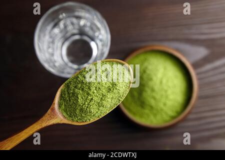 Congelare la polvere di erba del siero in un cucchiaio, una ciotola e un bicchiere d'acqua per il succo di disintossicazione. Concetto di stile di vita sano. Foto Stock