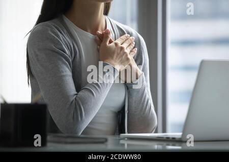 Primo piano su donna d'affari pia pacifica che tiene le mani sul petto Foto Stock