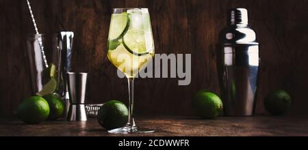 Cocktail Mojito con lime e menta in bicchiere di vino su sfondo ligneo. Banner panoramico con spazio per la copia Foto Stock