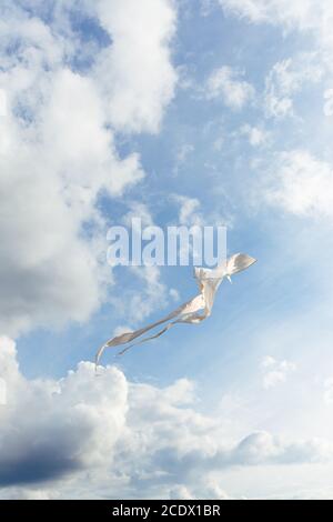 White kite battenti contro il cielo blu pieno di nuvole. L'immagine verticale Foto Stock