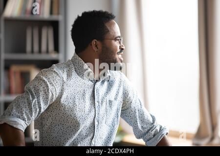 Sorridente sognante uomo afro-americano pensando al futuro o alle opportunità Foto Stock