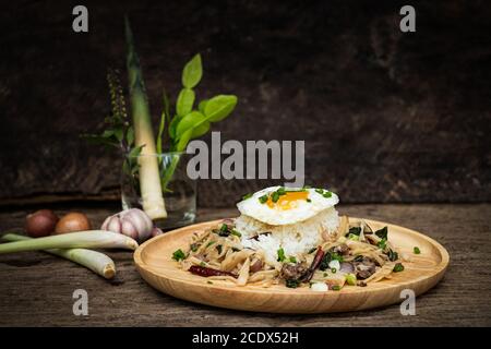 Carne fritta con germoglio di bambù e basilico santo servito con uova fritte di riso al vapore Foto Stock