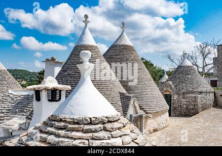 Gruppo di bellissimi Trulli, tradizionale capanna in pietra a secco pugliese vecchie case con tetto conico in Valle d'Itria, Puglia, Italia Foto Stock